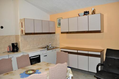 kuchnia z białymi szafkami, stołem i krzesłami w obiekcie Holiday Home Monte Maggiore w mieście Paz