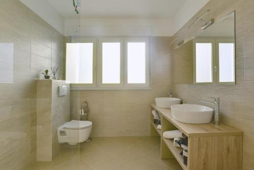 a bathroom with two sinks and a toilet and windows at House Bellissima in Vodnjan