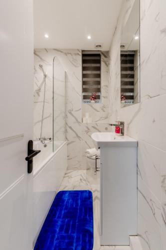 a white bathroom with a blue rug on the floor at Luxury flat Next to Hyde Park & Oxford Street in London
