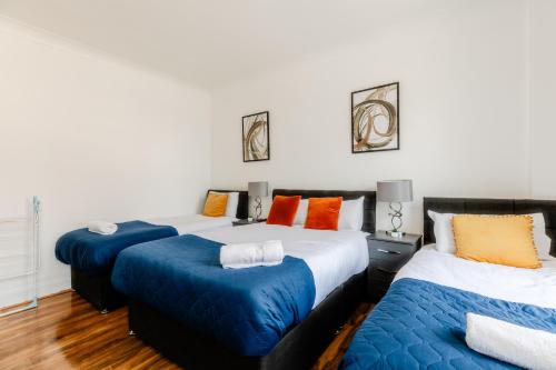 a bedroom with two beds with blue and orange pillows at Luxury flat Next to Hyde Park & Oxford Street in London