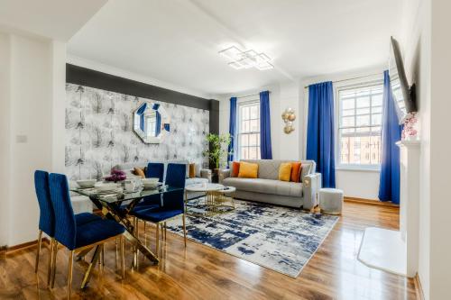 a living room with a glass table and blue chairs at Luxury flat Next to Hyde Park & Oxford Street in London