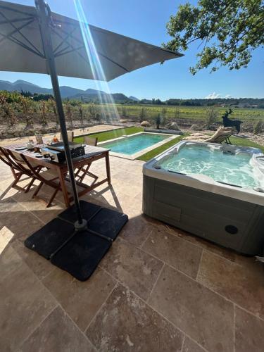 une terrasse avec un parasol et un bain à remous dans l'établissement Cabanon douillet rousset les vignes, à Rousset-les-Vignes