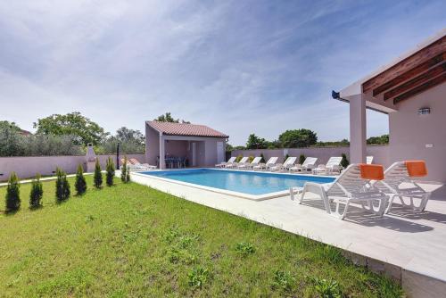 a swimming pool in a yard with chairs and a house at Villa Marcelia in Pula
