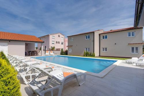a swimming pool with chaise lounge chairs next to a building at Villa Marcelia in Pula