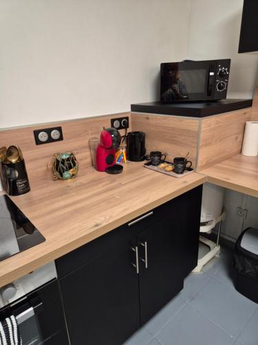 - une cuisine avec un comptoir en bois et un four micro-ondes dans l'établissement L'ébène-Grand T2-Raffiné-en Rez de Chaussée, à Saint-Gaudens