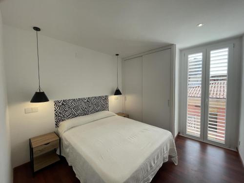 Un dormitorio blanco con una cama y una ventana grande. en Apartament Cervantes, en Palamós