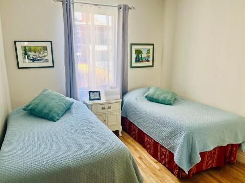two beds in a room with a window at Smiling house! 2 chambres, accueillant et spacieux in Montréal