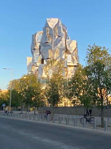 un grand bâtiment avec des arbres en face d'une rue dans l'établissement La Joliette Arles centre, à Arles