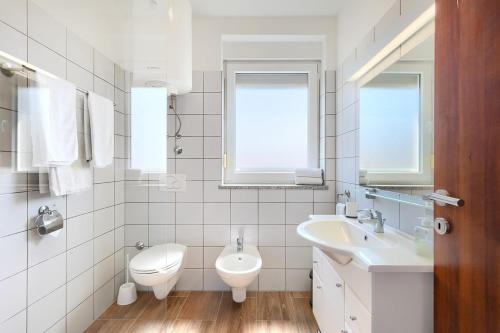 a white bathroom with a sink and a toilet at Villa Lara 1 in Ližnjan