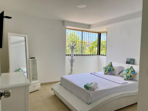 a white bedroom with a bed and a mirror at Apartamento Boutique Cartagena Plaza de Toros in Cartagena de Indias
