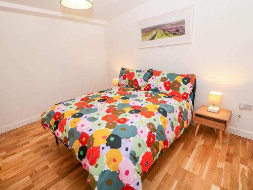 a bedroom with a bed with a colorful comforter at Yew Tree Cottage in Matlock