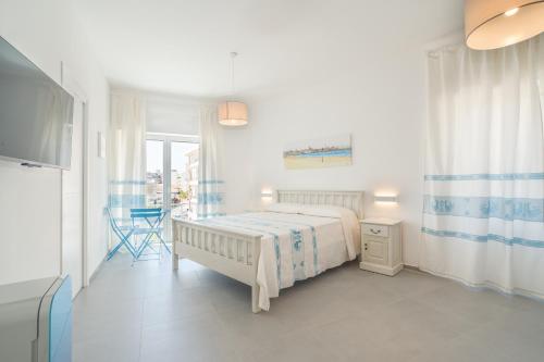 um quarto branco com uma cama e uma televisão em B&B S'Unda Jara em Alghero