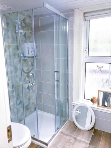 a bathroom with a shower with a toilet and a window at Crossroads Portsalon in Portsalon
