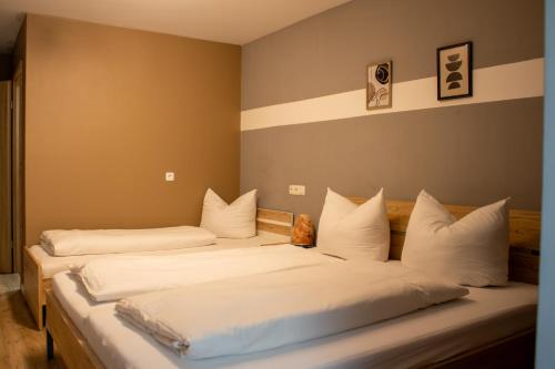 two beds in a room with white pillows at City House Alpeneck in Füssen
