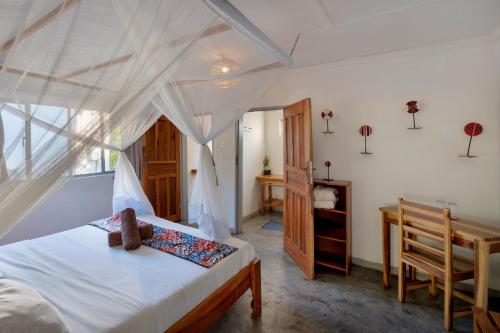 a bedroom with a canopy bed and a desk at Kamunjila Lodge in Livingstone