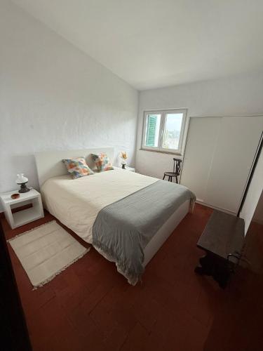 a white bedroom with a large bed and a window at Casa da Ingrina in Raposeira