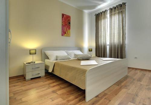 a bedroom with a large bed with a night stand and a window at Villa Iva in Medulin