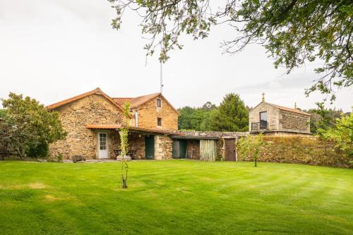 an old stone house with a green lawn at Casa 1 LarSanAdrian in Coristanco