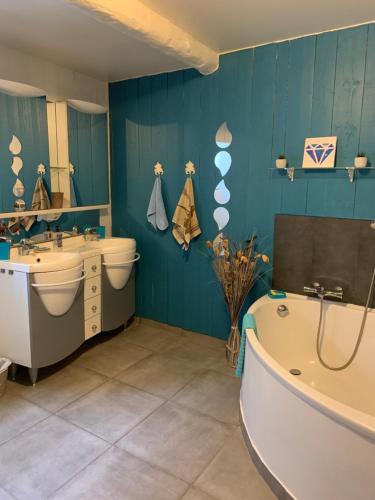 La salle de bains est pourvue de murs bleus, d'une baignoire et d'un lavabo. dans l'établissement Laudacieuse, à Cazouls-lès-Béziers