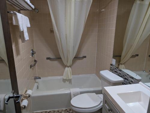 a bathroom with a toilet and a tub and a sink at Travelodge by Wyndham Forsyth in Forsyth