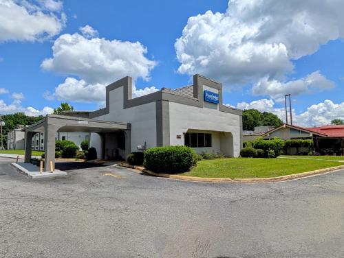 a large white building with a parking lot at Travelodge by Wyndham Forsyth in Forsyth