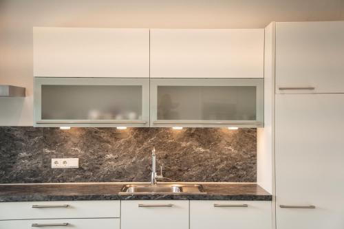 a kitchen with white cabinets and a sink at Apartment Villa Laurin in Pianizza di Sotto