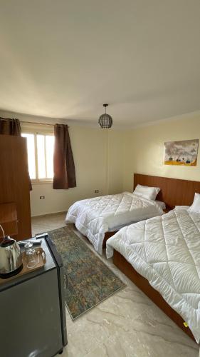 a hotel room with two beds and a table at ALADDIN PYRAMIDS View in Cairo