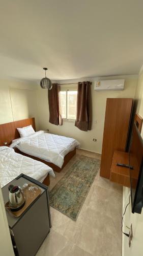 a hotel room with two beds and a television at ALADDIN PYRAMIDS View in Cairo