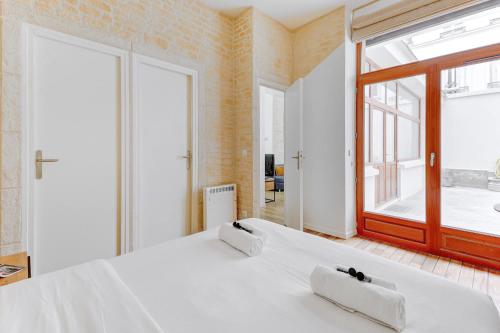 - une chambre avec un grand lit blanc et une grande fenêtre dans l'établissement Sublime appartement a 100 metres Jardin du Luxembourg, à Paris