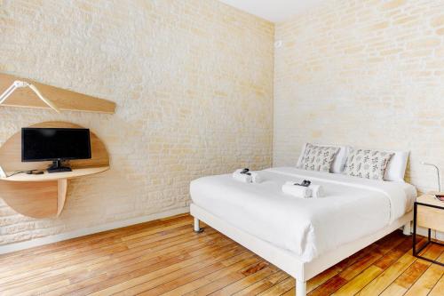 une chambre blanche avec un lit et une télévision dans l'établissement Sublime appartement a 100 metres Jardin du Luxembourg, à Paris