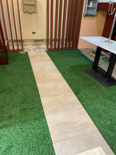 a floor covered in green grass next to a table at Da palm Inn in Aburi