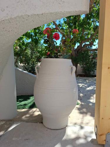 a large white planter with red flowers in it at Grammeno Seaside Studios in Palaiochóra