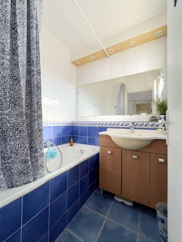 La salle de bains est pourvue de carrelage bleu, d'une baignoire et d'un lavabo. dans l'établissement Maison Bord de Mer 6 à 7 pers au Grau du Roi, au Grau-du-Roi