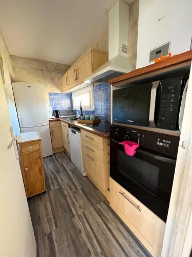 une cuisine avec des armoires en bois et un appareil noir dans l'établissement Maison Bord de Mer 6 à 7 pers au Grau du Roi, au Grau-du-Roi