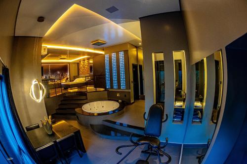 a bathroom with a tub and a chair in a room at Ragam Motel Empreendimentos Hoteleiros in Ponta Grossa
