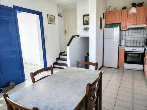 a kitchen with a table with chairs and a refrigerator at Cycladic Horizon Island Villa By Hostandros in Batsi