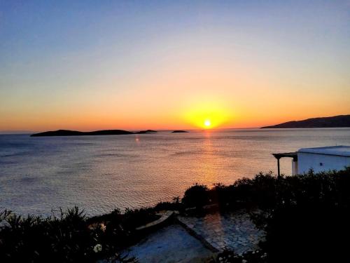 a sunset over a body of water with the sun setting at Cycladic Horizon Island Villa By Hostandros in Batsi