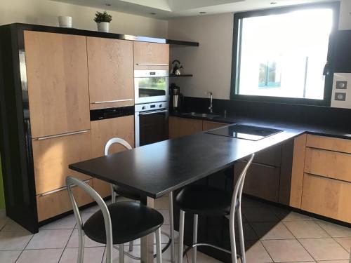 une cuisine avec une table et des chaises noires dans l'établissement Maison calme, vue sur mer, à Saint-Pabu