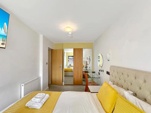 a bedroom with a large bed with a yellow blanket at Granada Apartments Berkeley in Blackpool