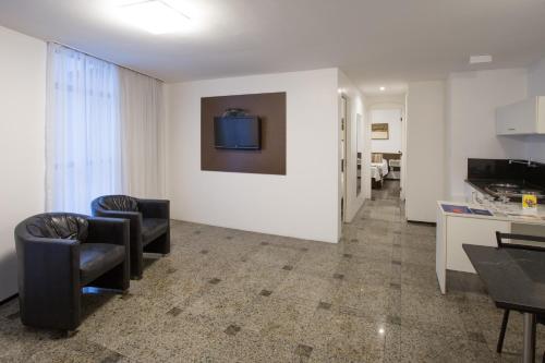 a living room with chairs and a table and a kitchen at Hotel Brasil Tropical in Fortaleza