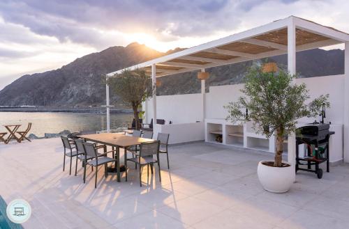 a patio with a table and chairs and a grill at Al Dana, Sea Breeze Villa, Fujairah in Fujairah