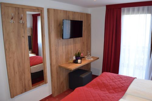 a bedroom with a bed and a mirror and a tv at Hotel Am Siebersturm in Rothenburg ob der Tauber