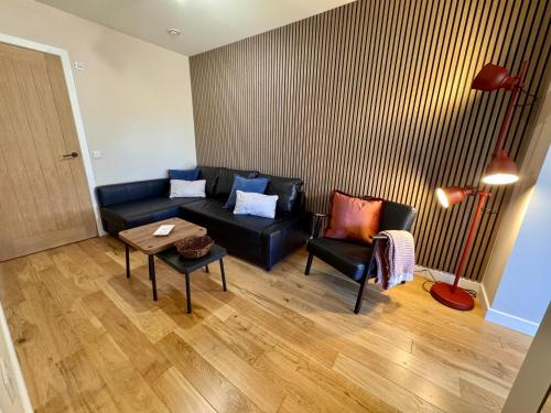 a living room with a black couch and a table at The Hebridean - Rooms & Apartments in Broadford