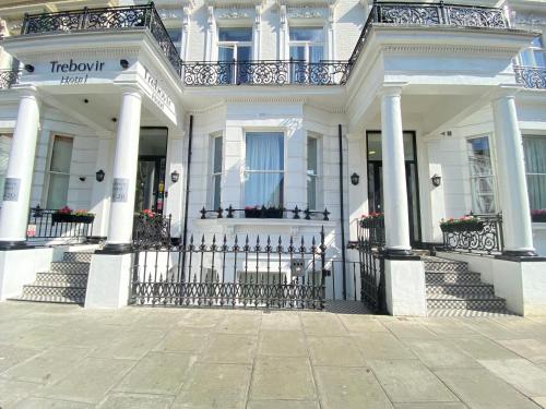 a white house with columns and a fence at Trebovir Hotel in London