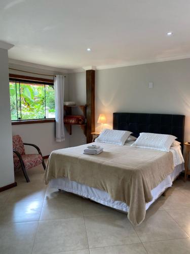 a bedroom with a large bed and a window at Chalé Aconchego da Paz - Chalé 1 in Lavras Novas