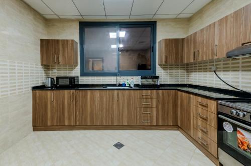 a kitchen with wooden cabinets and a sink at Al Dana, Sea Breeze Villa, Fujairah in Fujairah