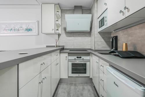 a kitchen with white cabinets and a stove top oven at Puerto Cruz Relaxing Shared Pool in Puerto de la Cruz