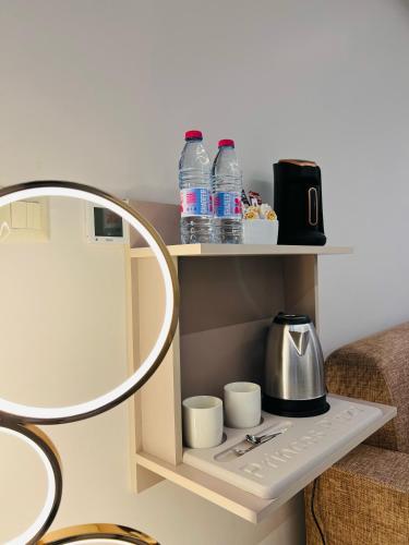 a shelf with bottles of water and cups on it at فندق الأمراء بلازا in Ma‘ān