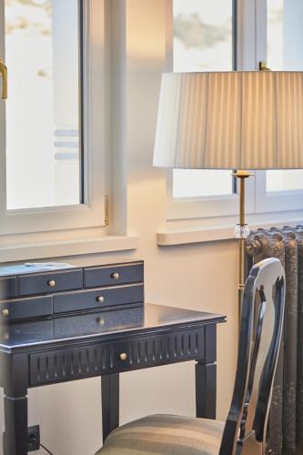 a desk with a lamp next to a chair at Silken Gran Hotel del Sella in Ribadesella