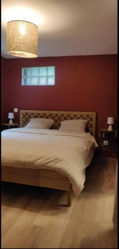 une chambre avec un grand lit avec un mur rouge dans l'établissement La Datcha d Elvira - Maison de campagne au vert, à Levroux